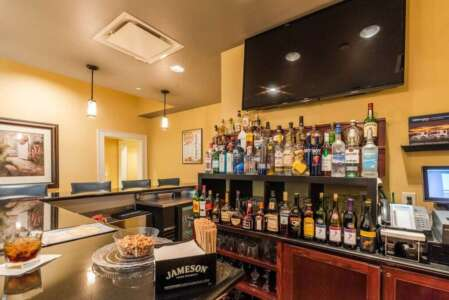 Bar with bottles of liquor on shelves, TV, and customers at tables.