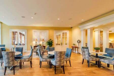 Elegant dining room with blue patterned chairs, round tables, and French doors.