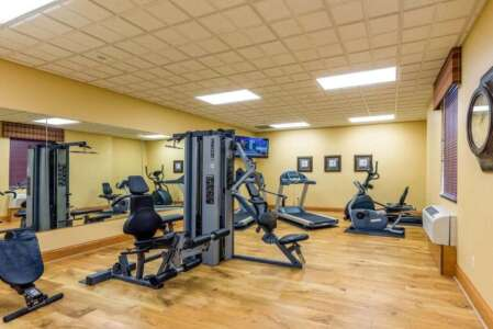 Hotel fitness center with exercise machines, mirrors, and TV.