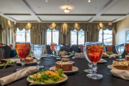 Table set for a meal in a dining room. Food, drinks, and napkins arranged on black tablecloth.