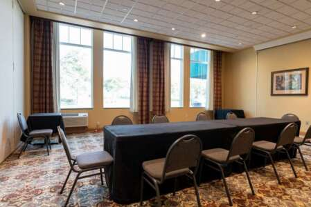 Meeting room with rectangular table covered in black and chairs.