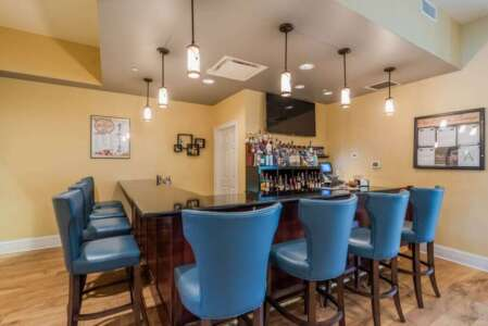 A bar with blue stools, liquor bottles, and hanging lights.