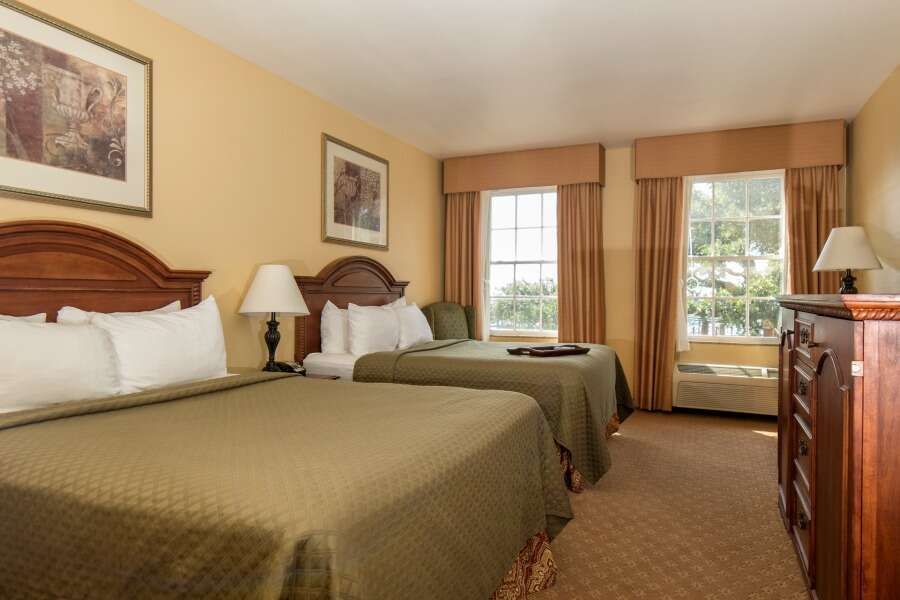 Hotel room with two double beds, windows, and a dresser.