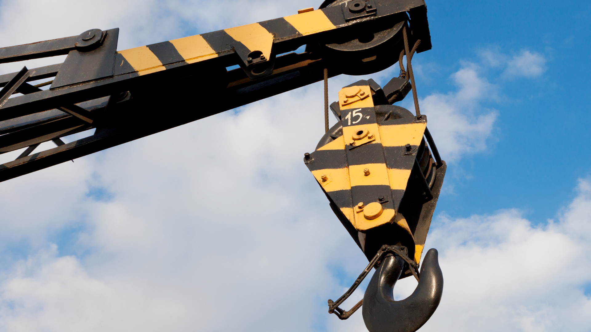 Yellow mobile crane lifting concrete panels at a construction site.