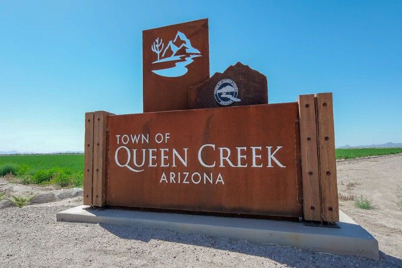 Town of Queen Creek, Arizona sign beside a desert road under a blue sky