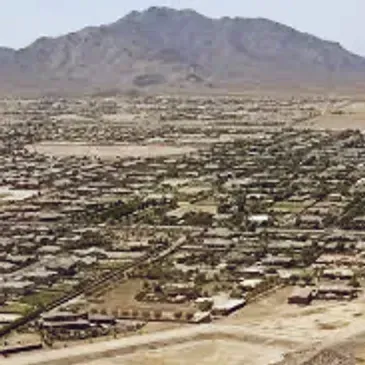 Aerial view of a sprawling desert town with a mountain in the background