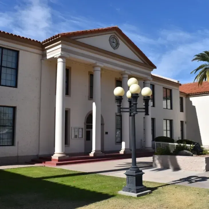Classical building with white columns, red roof, and a black streetlamp in front under a blue sky