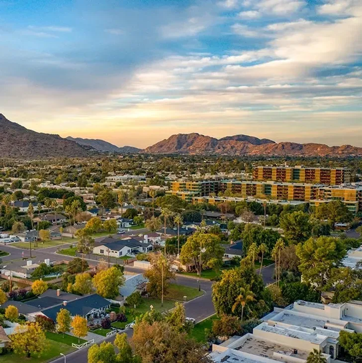 Sunset over a suburban neighborhood with mountains in the distance and a colorful apartment complex