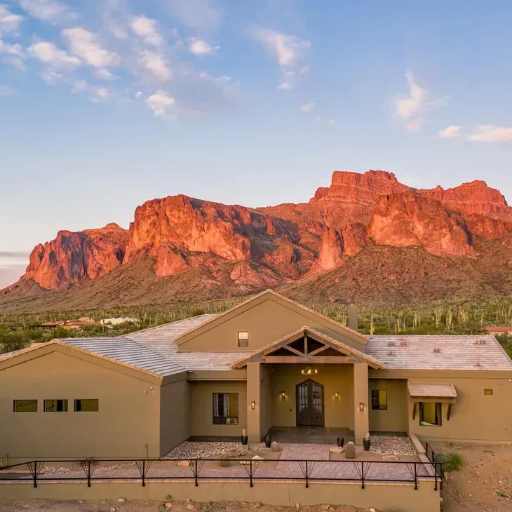 Modern house beneath red desert cliffs at sunset