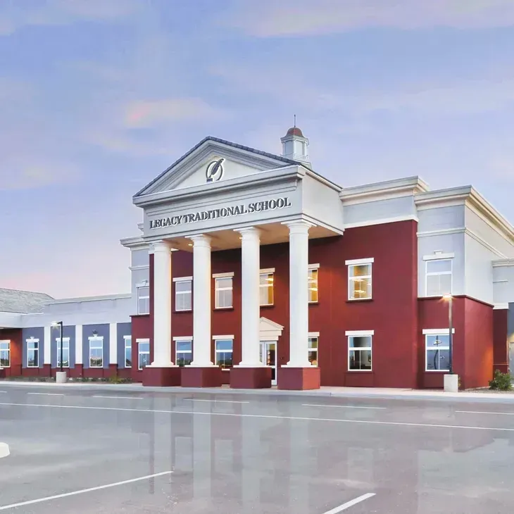 Front view of a red-and-white church with columns and a steeple beside an empty parking lot