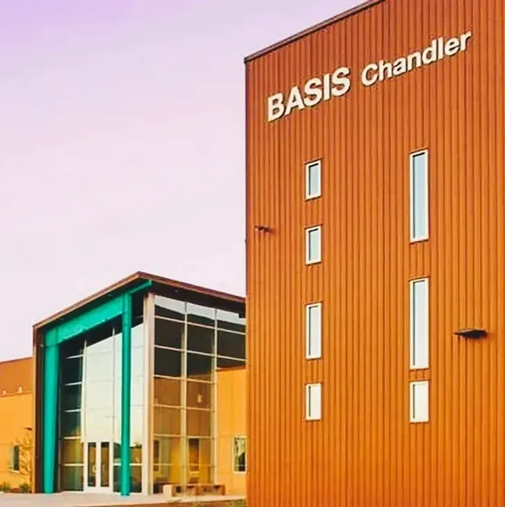 BASIS Chandler school building with orange facade and glass entrance at sunset