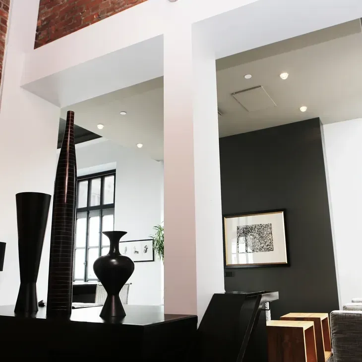 Modern living room with black vases, white columns, recessed lights, and a dark accent wall