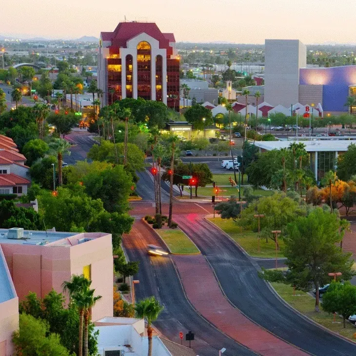 Curving road through a green cityscape with tall buildings at sunset