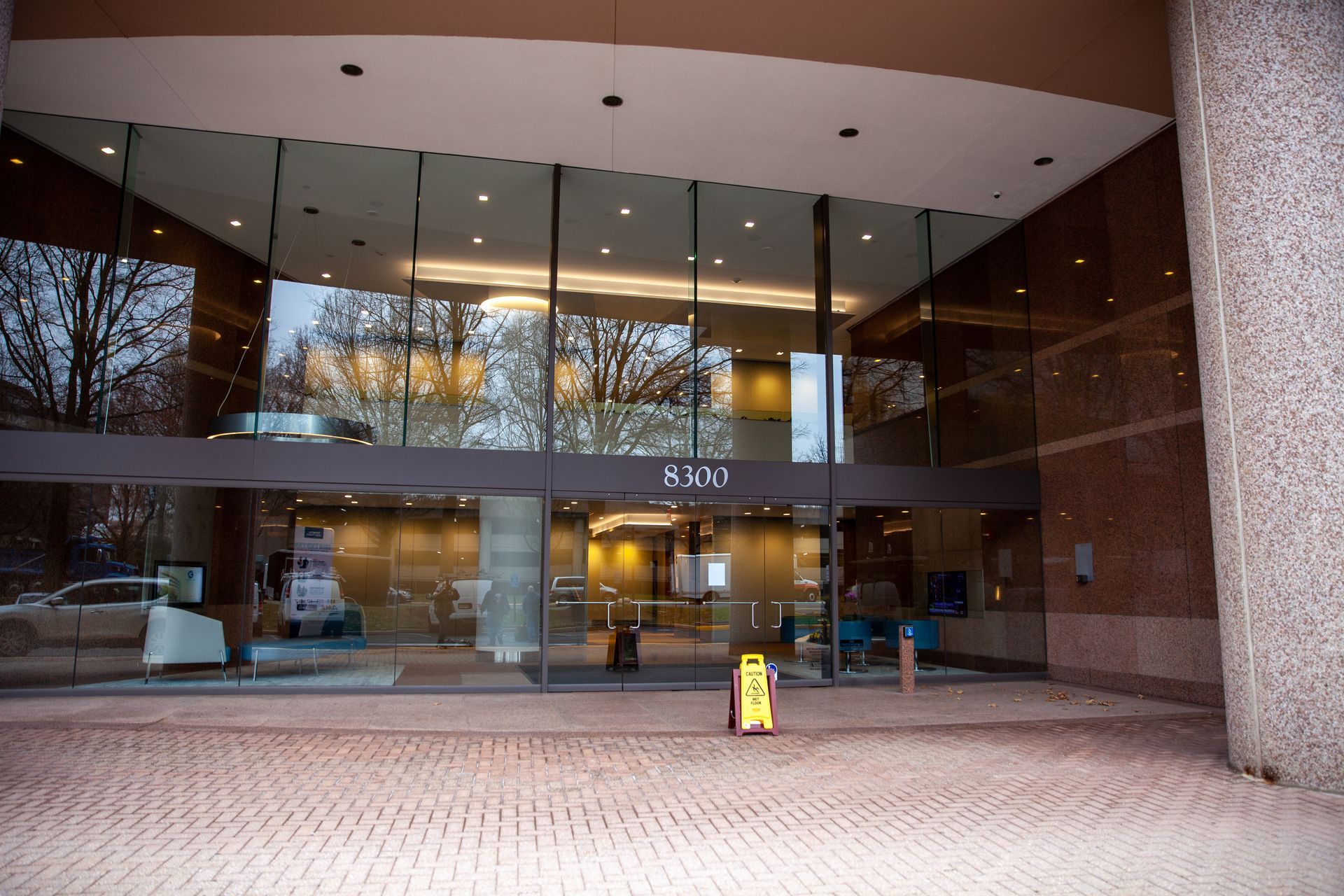 Entrance of a building with glass doors and a stone facade, featuring a 