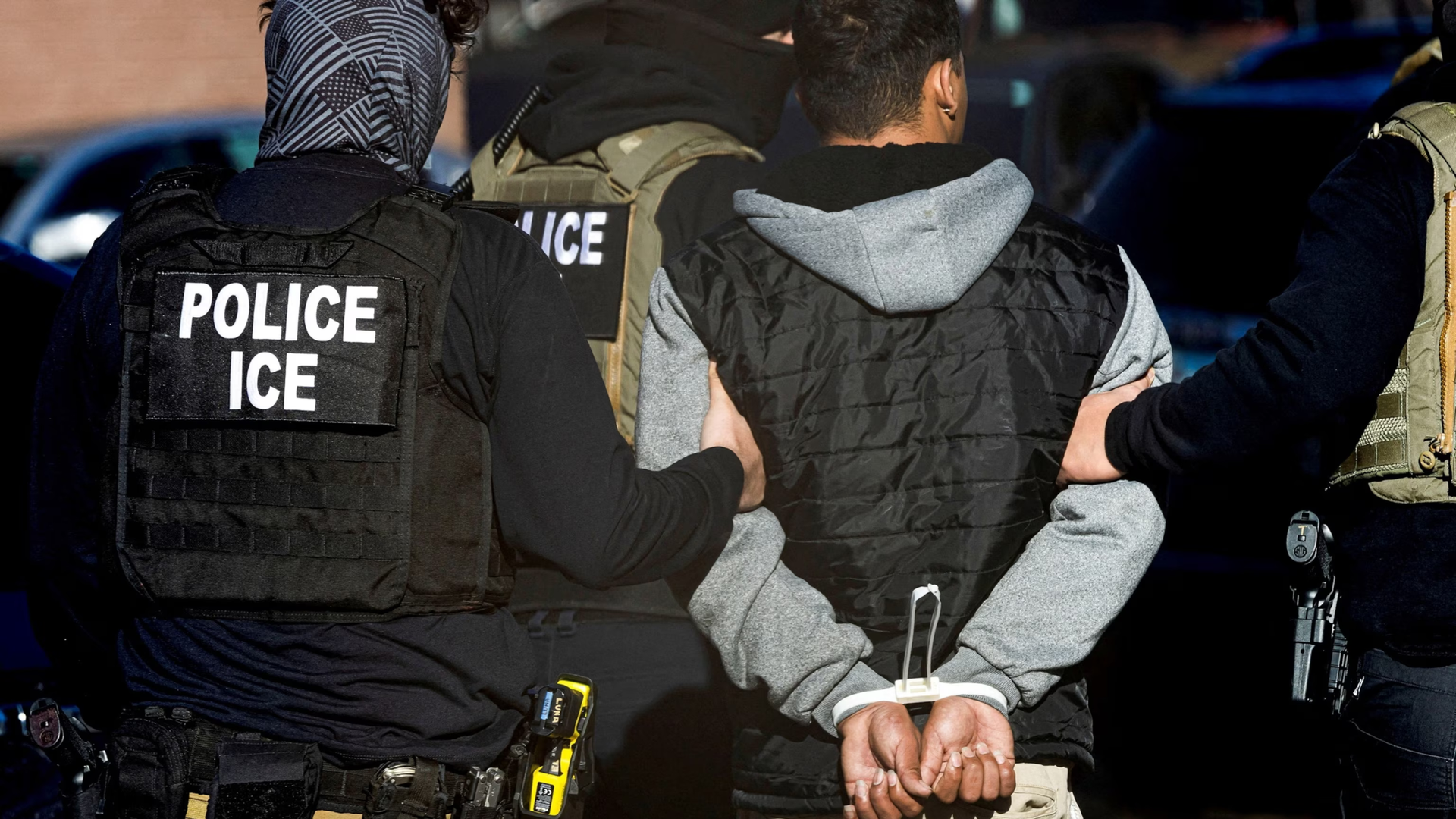 ICE officers arresting a person in handcuffs.
