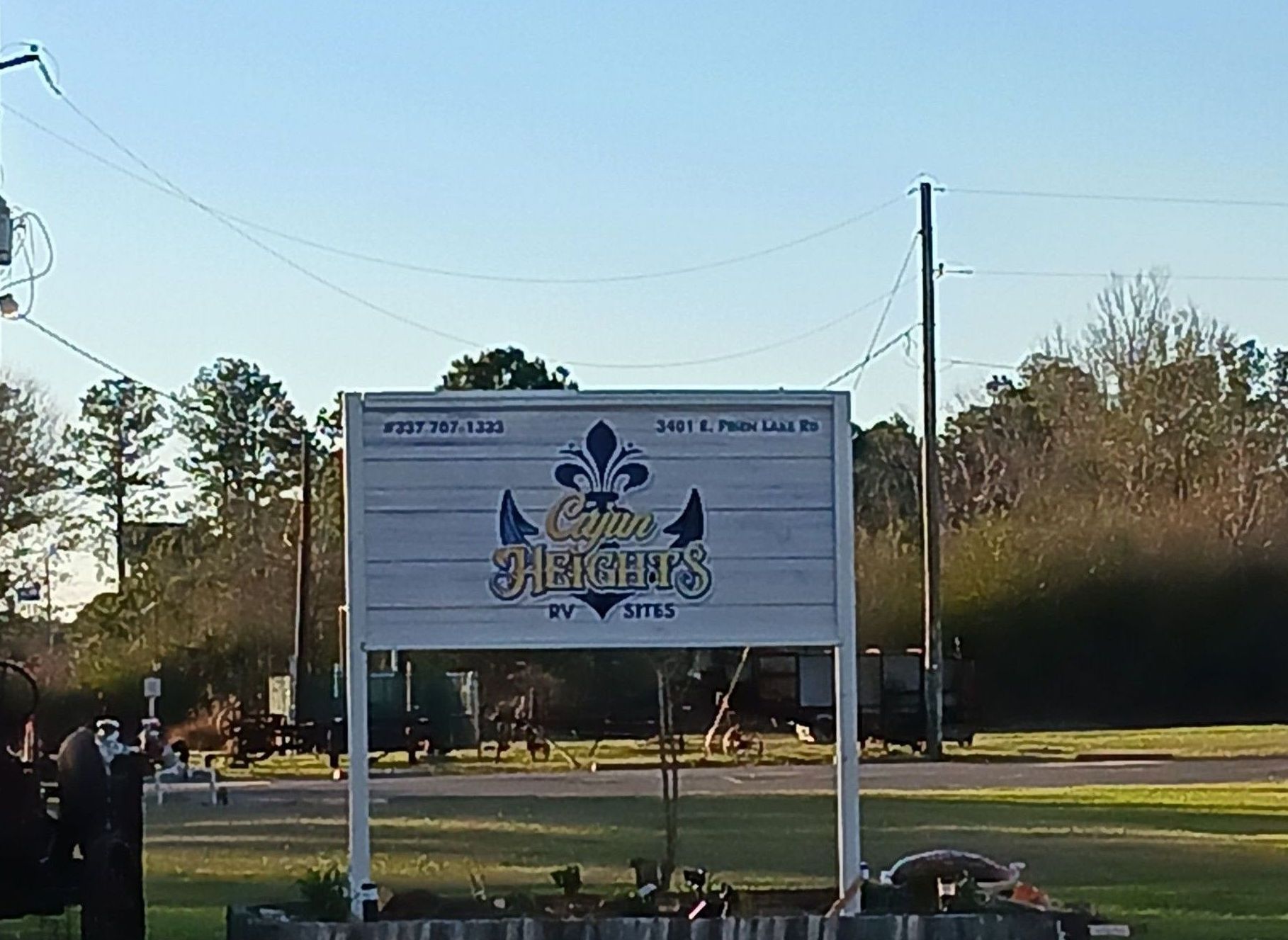 Roadside sign with blue logo in a grassy field under a clear sky.