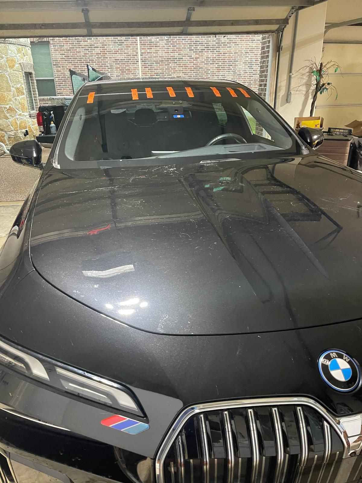 Black BMW car in a garage; orange tape across the windshield.
