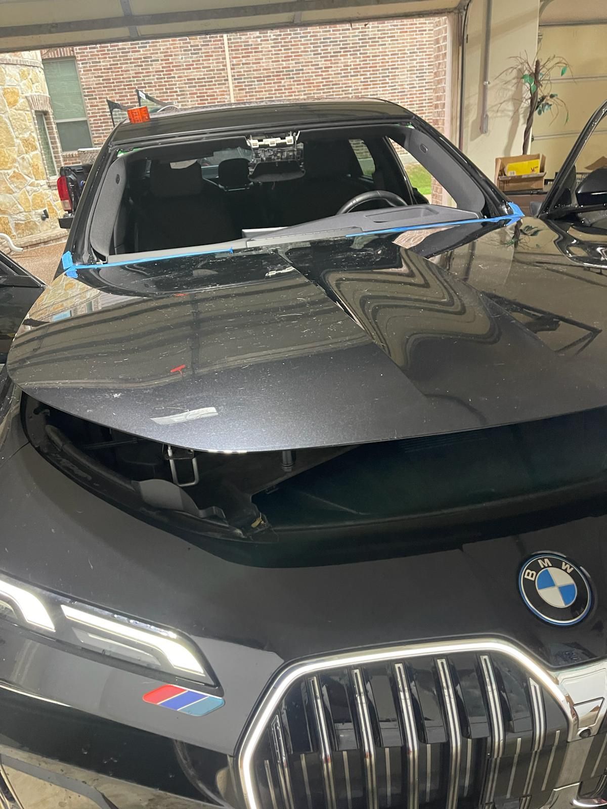 Black BMW with missing windshield, in a garage, front view.