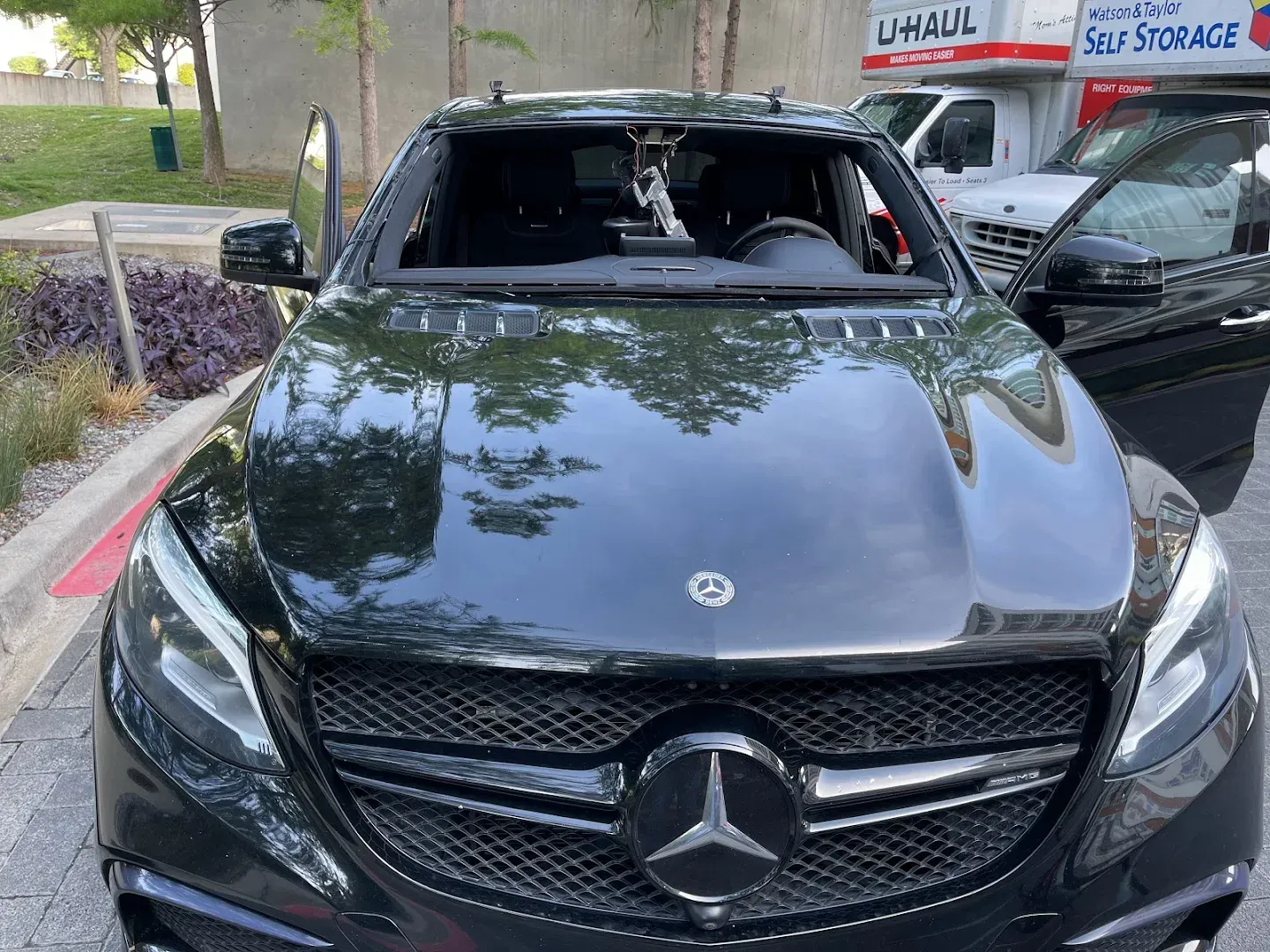 Black Mercedes SUV with a shattered windshield, parked outdoors.