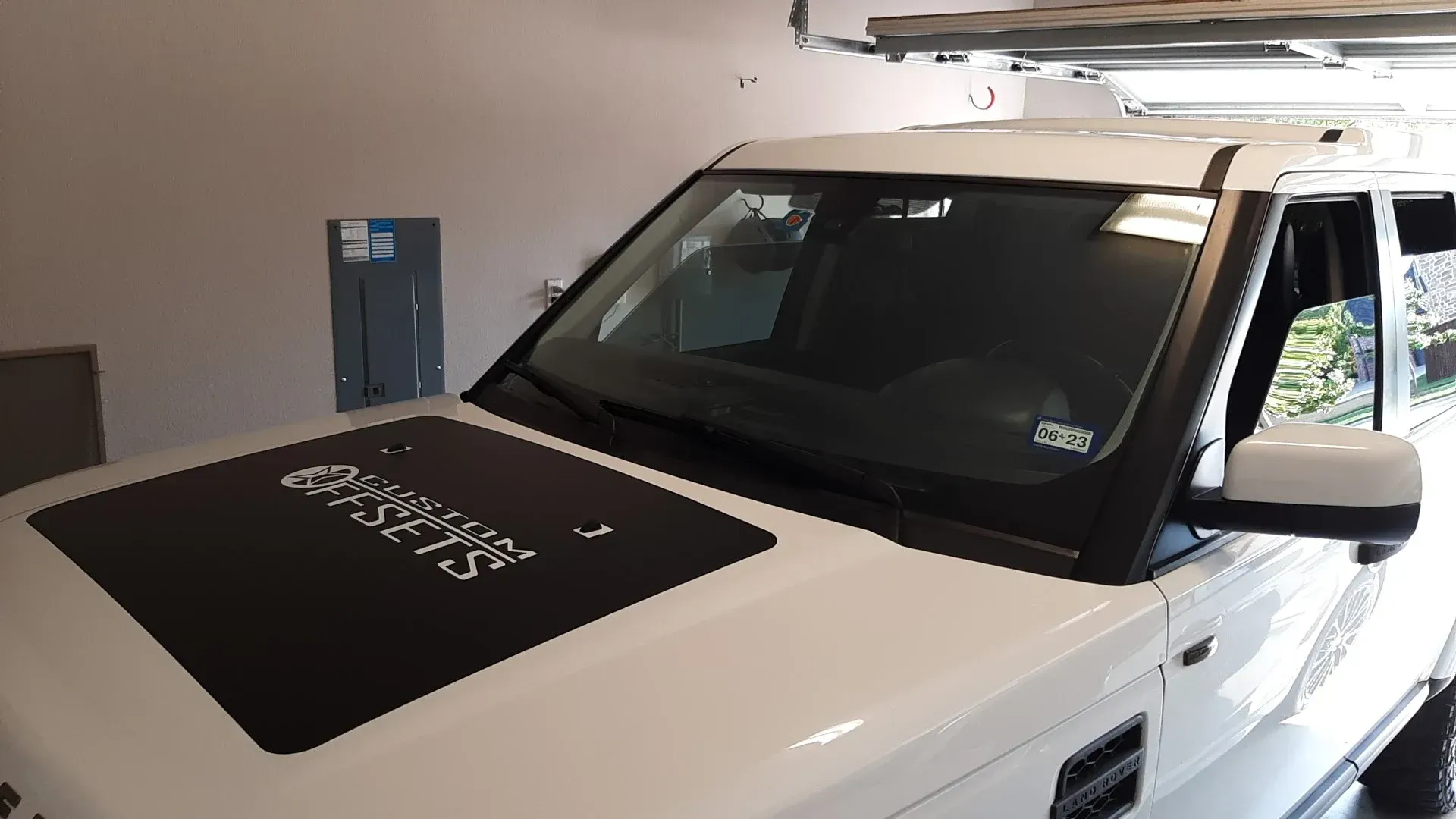 White SUV with black hood decal parked in a garage.