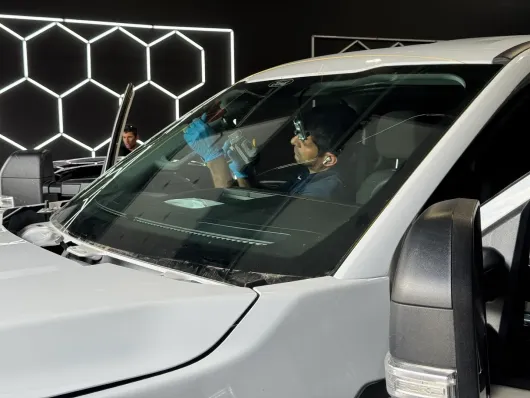 Car windshield replacement with suction cups, shop interior.