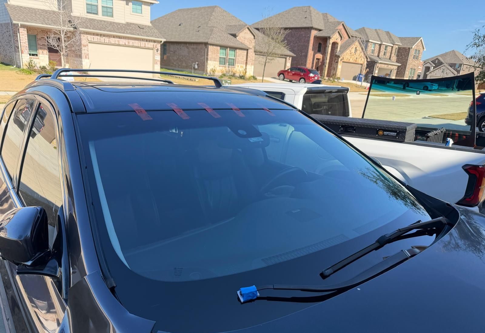 Black SUV with tinted windshield and roof rack, parked in a suburban driveway.