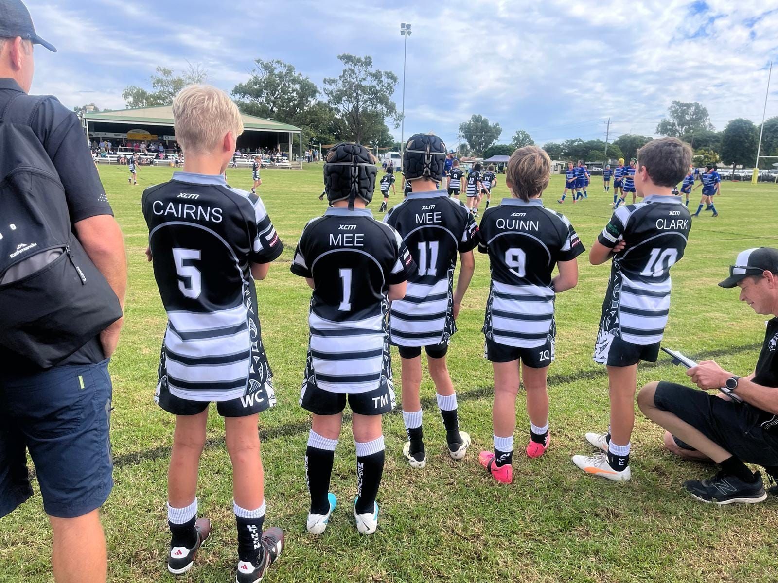 A group of young boys wearing black and white striped jerseys with the number 5 on the back