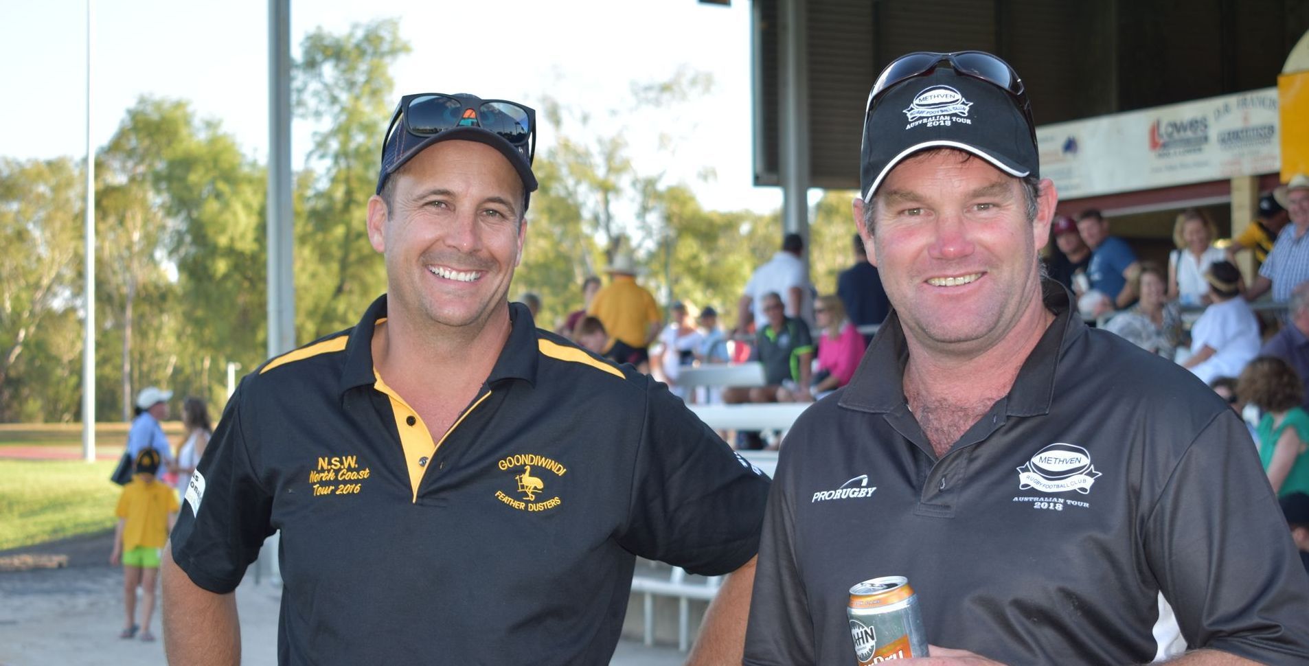Two men standing next to each other with one holding a can of soda