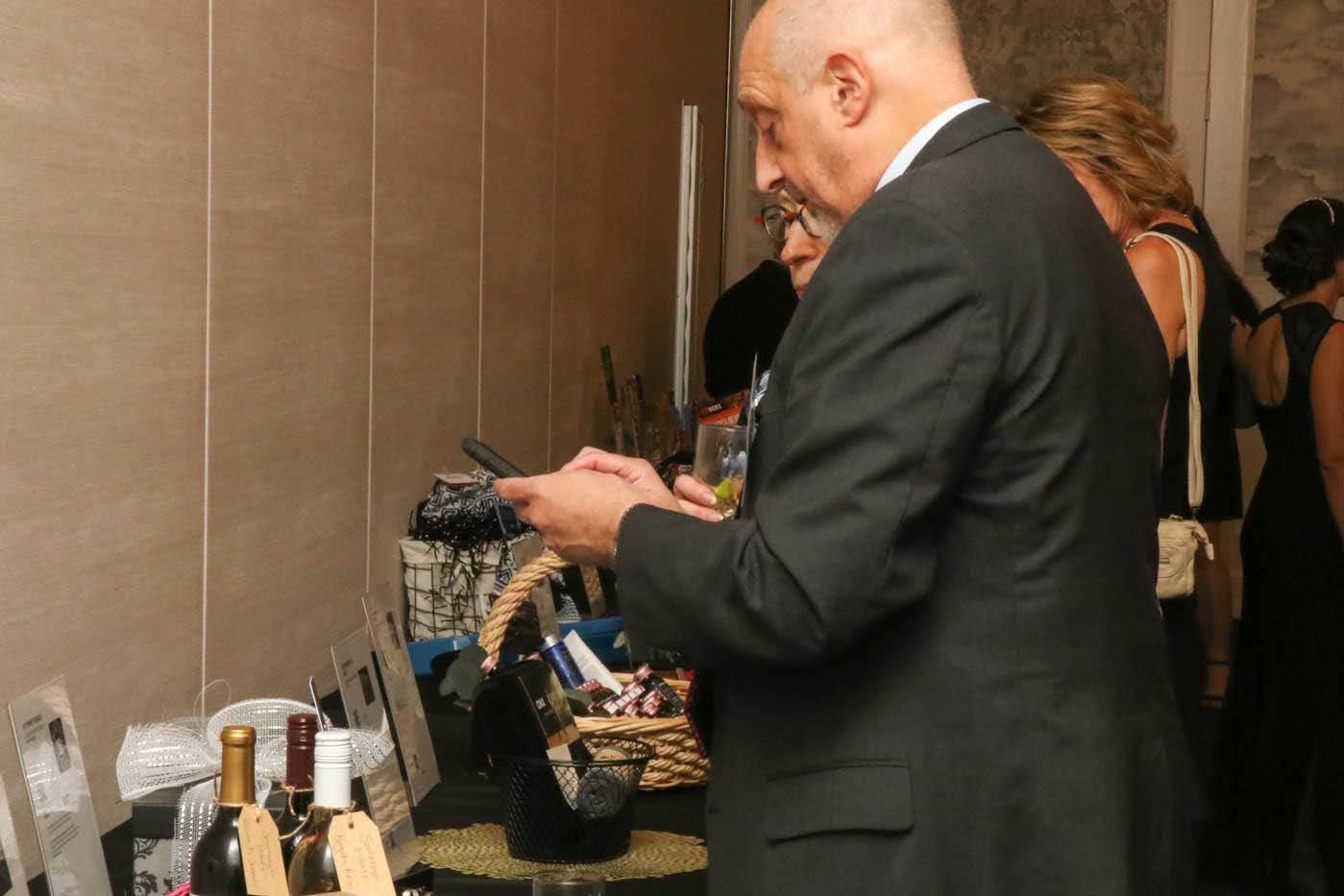 Man in suit looking at items on a display table at an event.