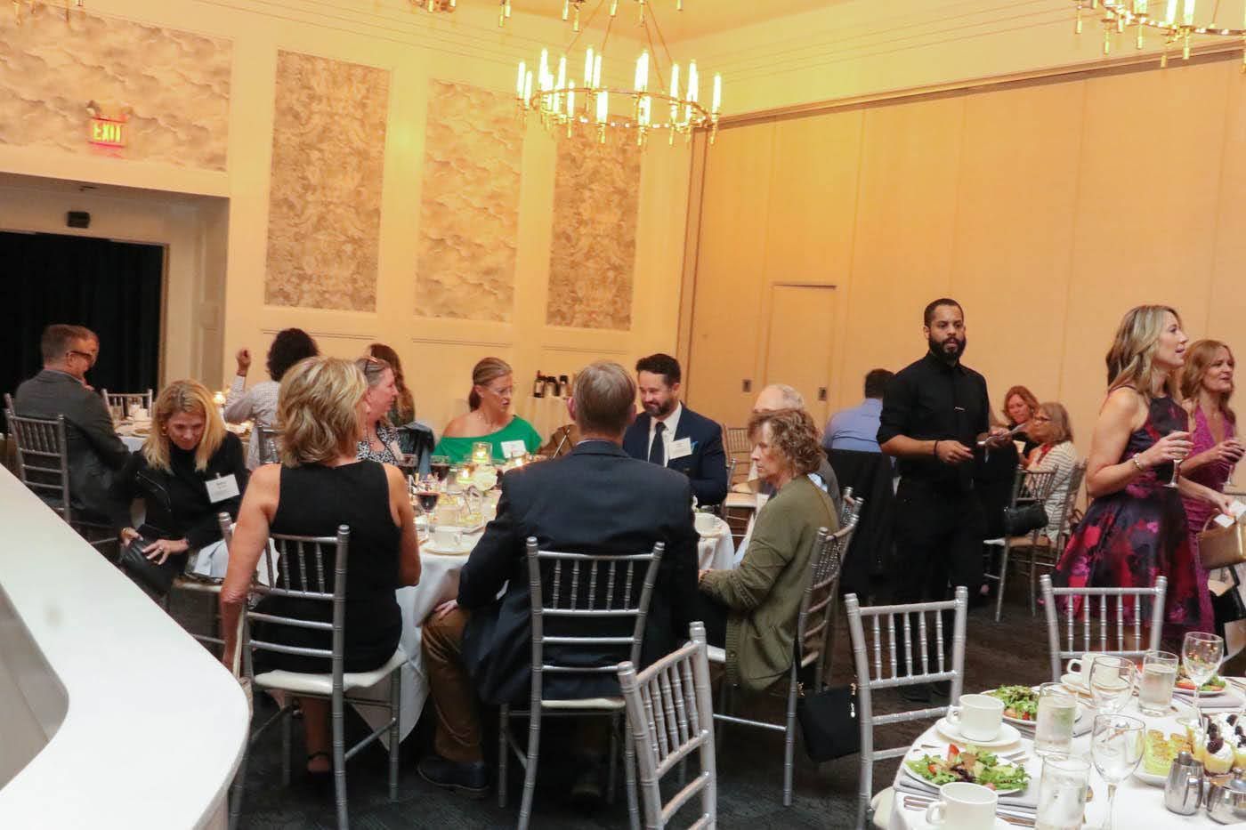 People seated at tables in a brightly lit banquet hall.