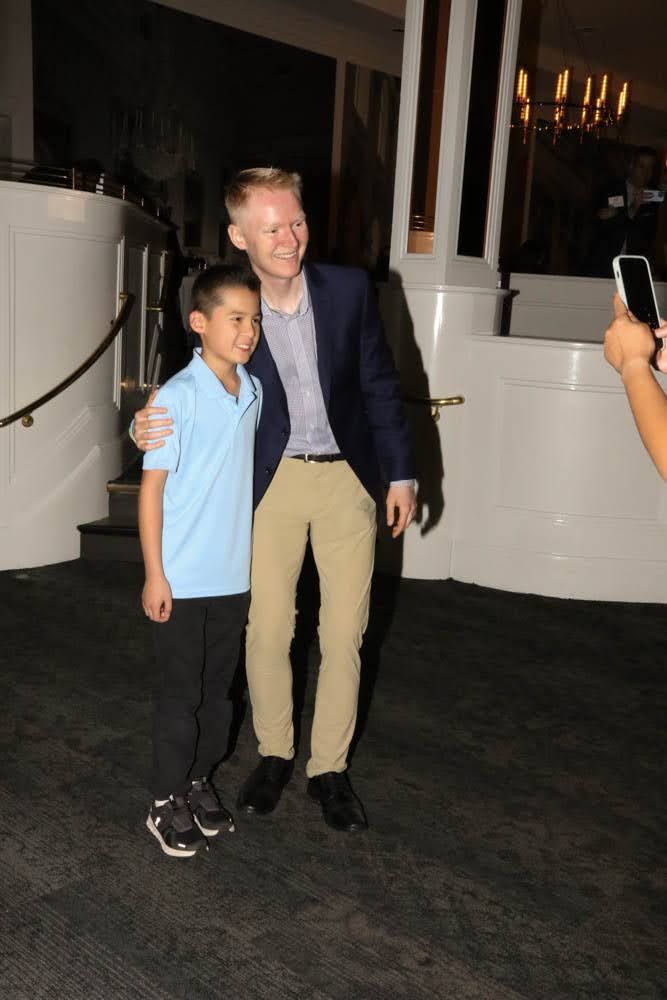 Man in blazer and boy in polo shirt pose for photo indoors.
