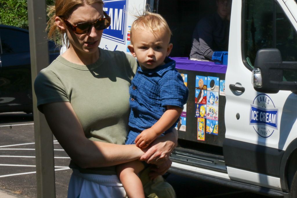 Woman holding a child near an ice cream truck; child looks at the camera.