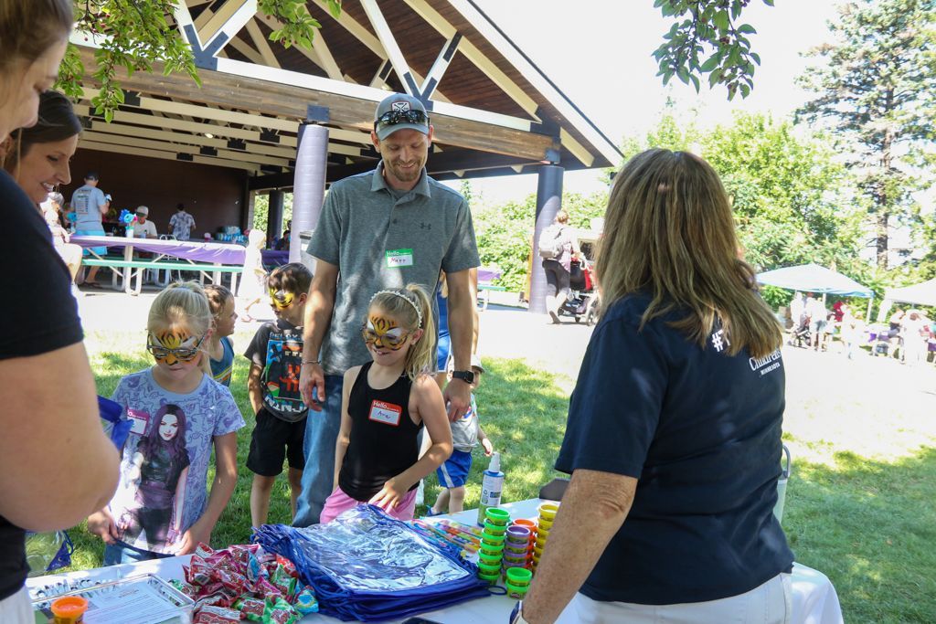 People at a park event with face painting, treats, and a pavilion.