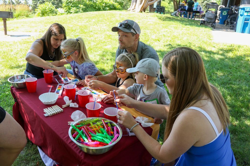 Family at outdoor table crafting with supplies in bowls and cups.