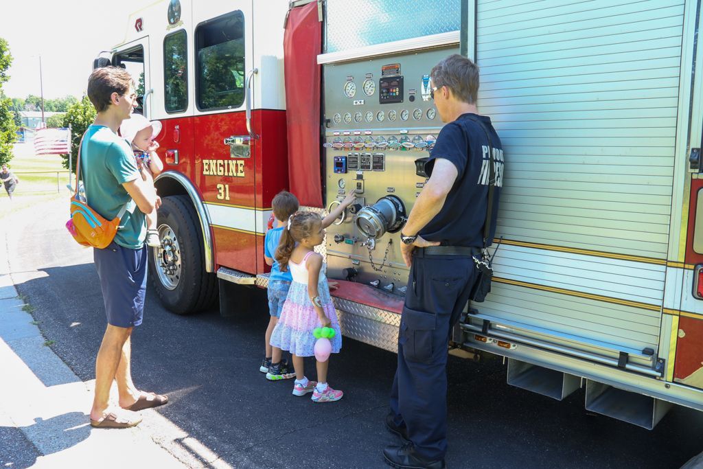 Firefighter shows children fire truck equipment.