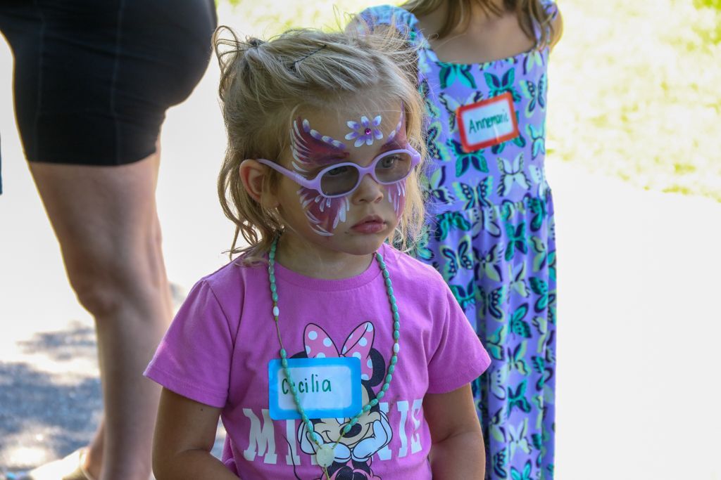 Girl with face paint, a pink shirt, and a nametag.
