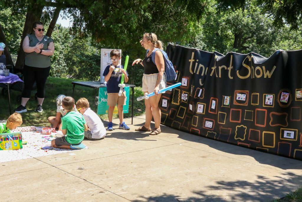 Children at an outdoor art show. A banner reads 
