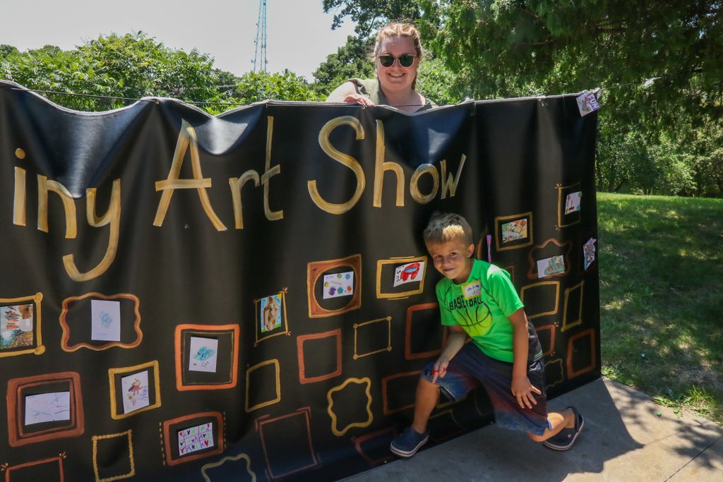 Woman and boy stand behind a black banner that reads 