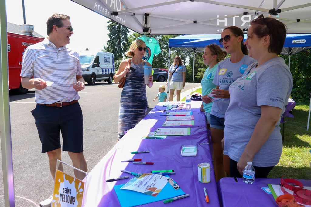 People at a table with writing supplies, under a tent outdoors, with a food truck in the background.