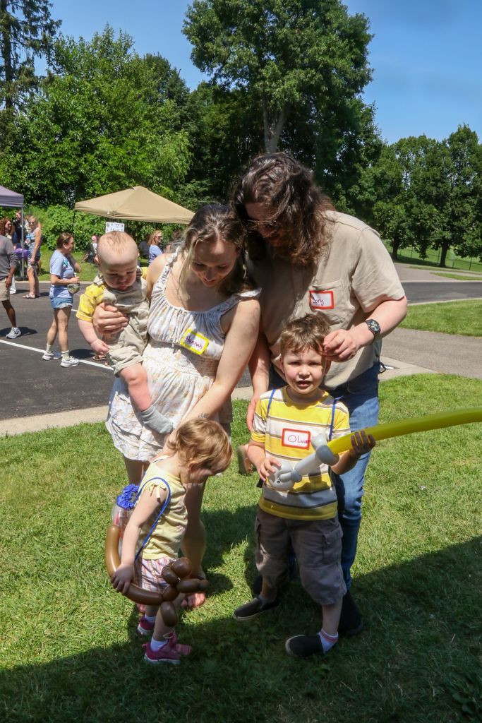 Family of five at an outdoor event with a yellow ribbon. Children with balloon animals.