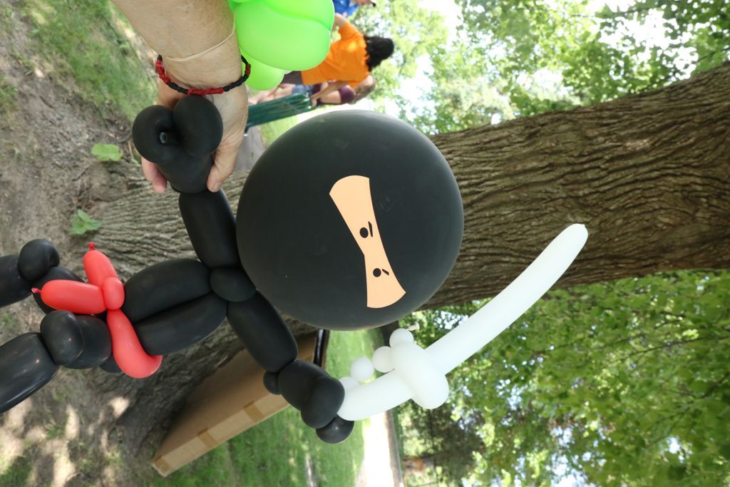 Balloon ninja with sword and red sash; black and white balloons against a tree.