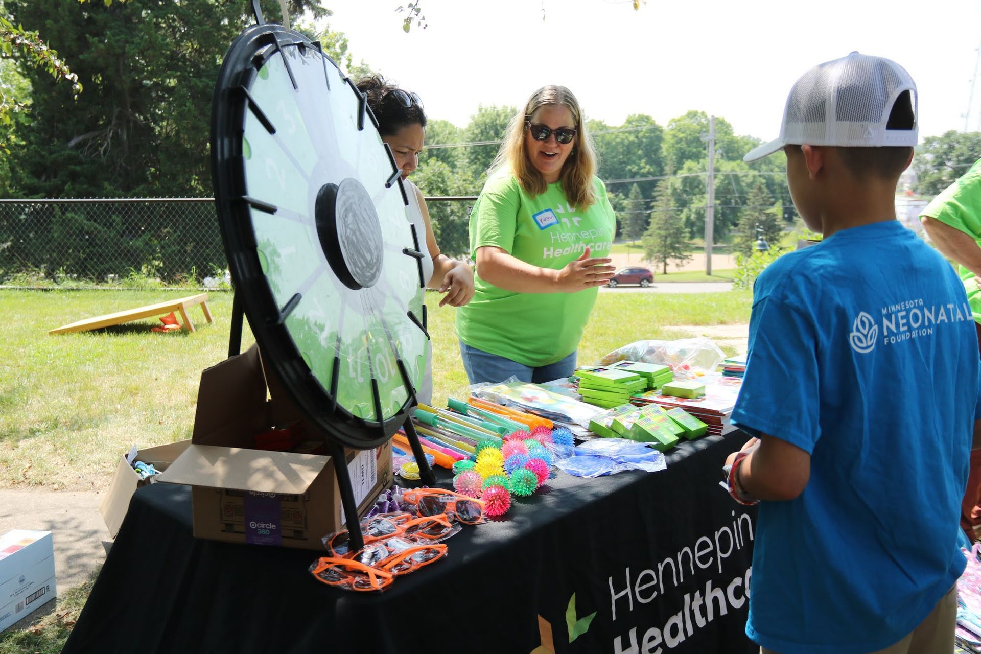 People playing a spin wheel game at an outdoor event table.