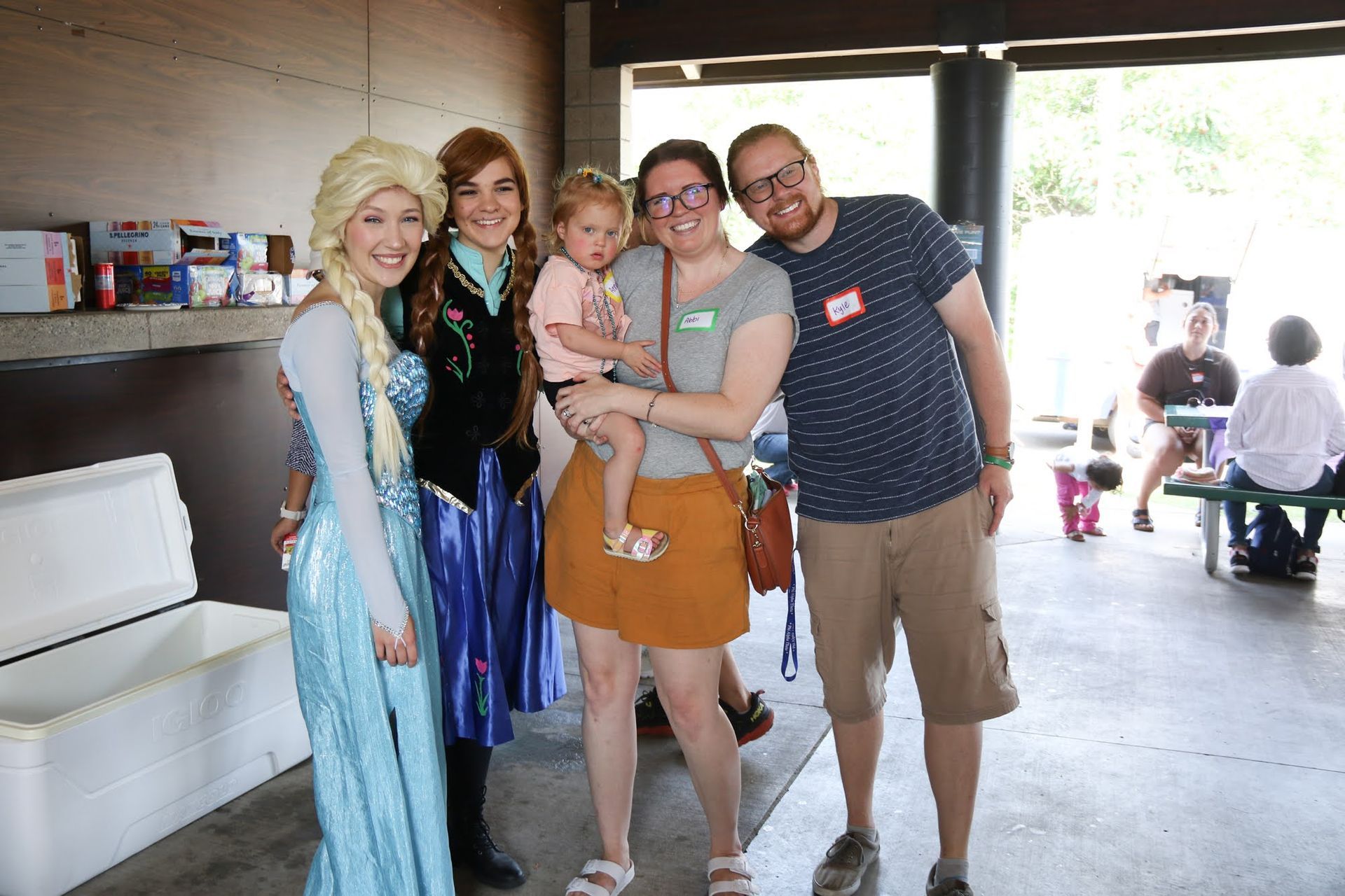 People pose with costumed characters. Outdoors, smiling, sunny day.