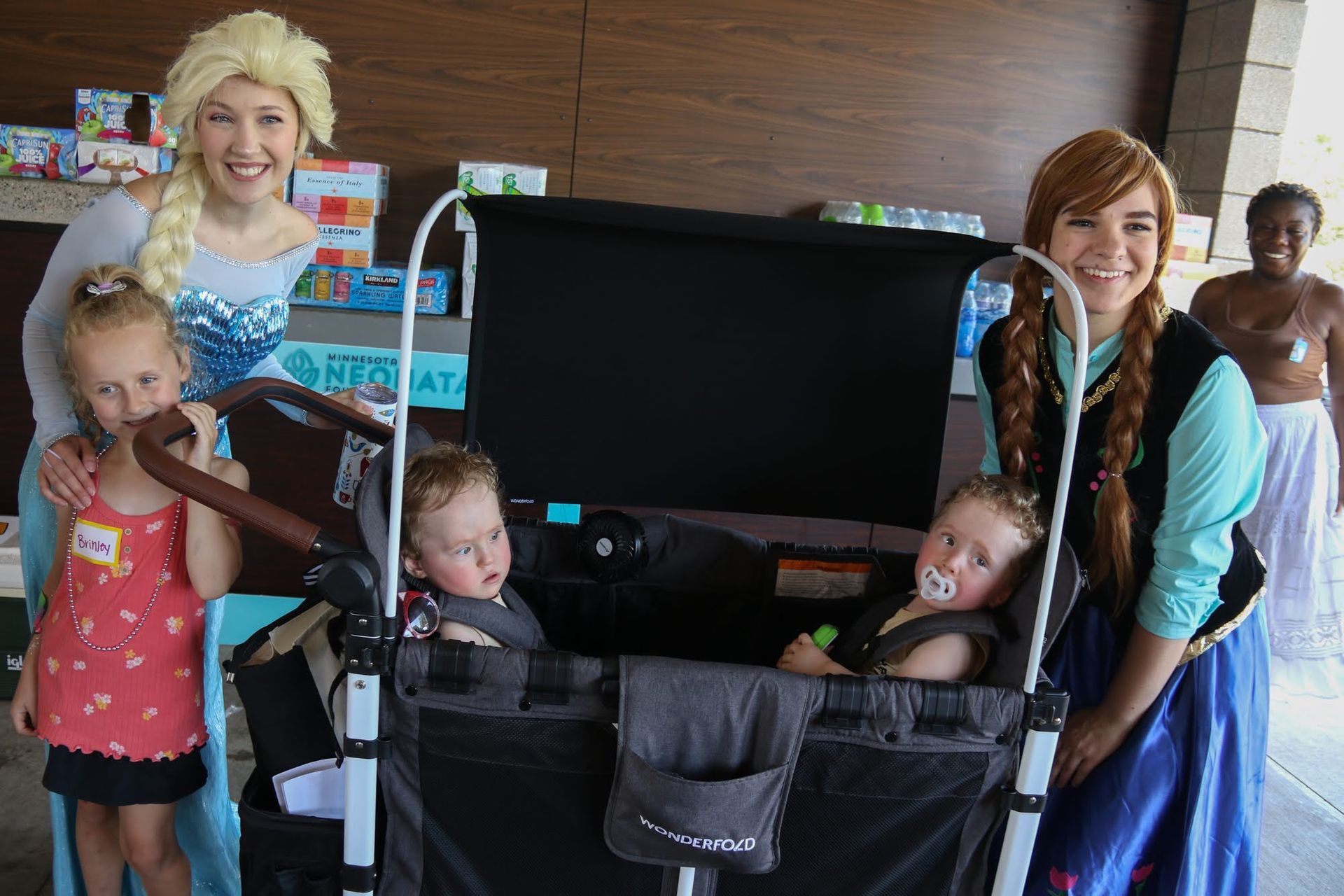 Elsa and Anna with children in a wagon. Two little girls and two babies with characters.