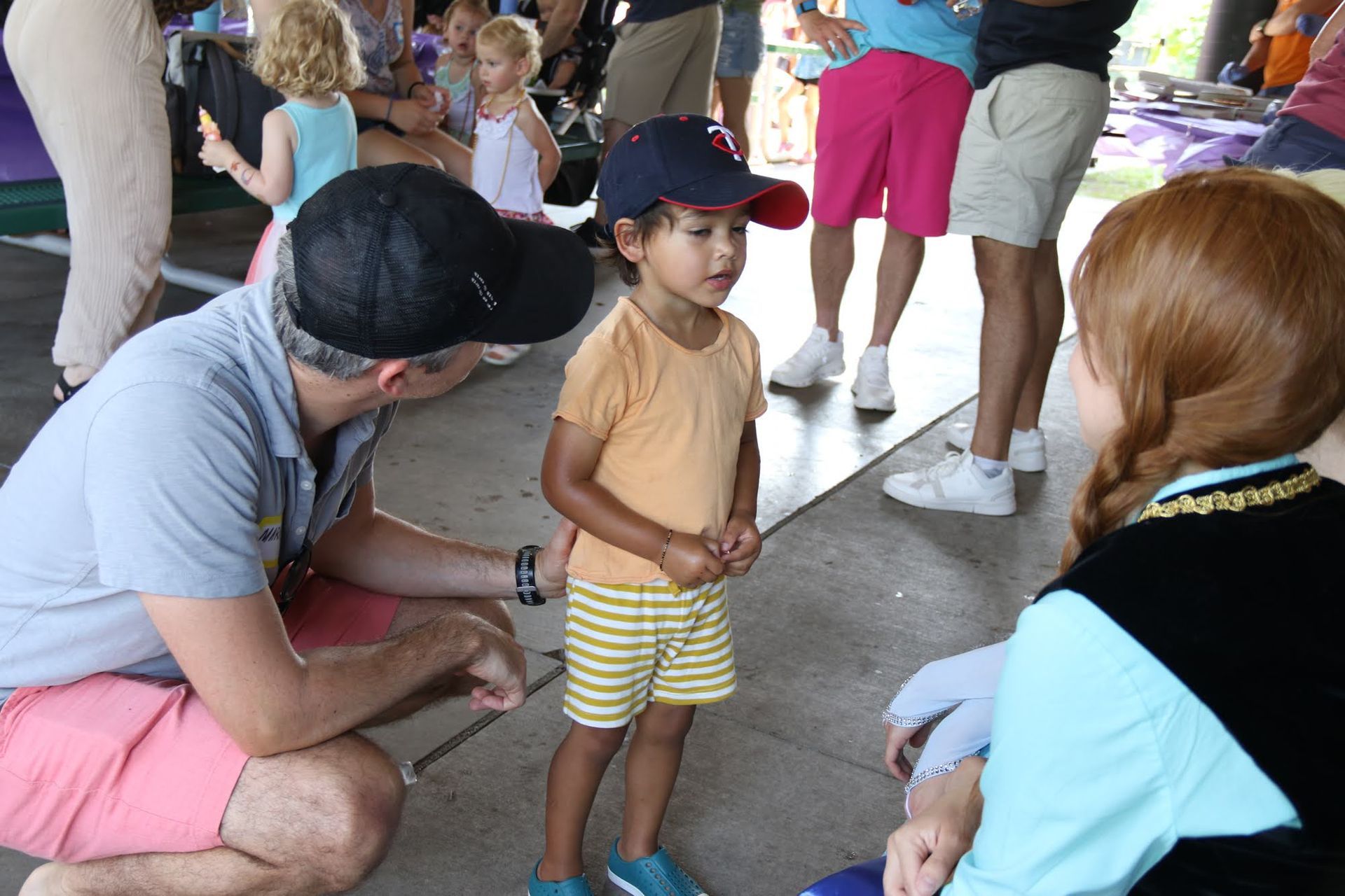 Child talking to a person dressed as a princess, man kneeling beside them.