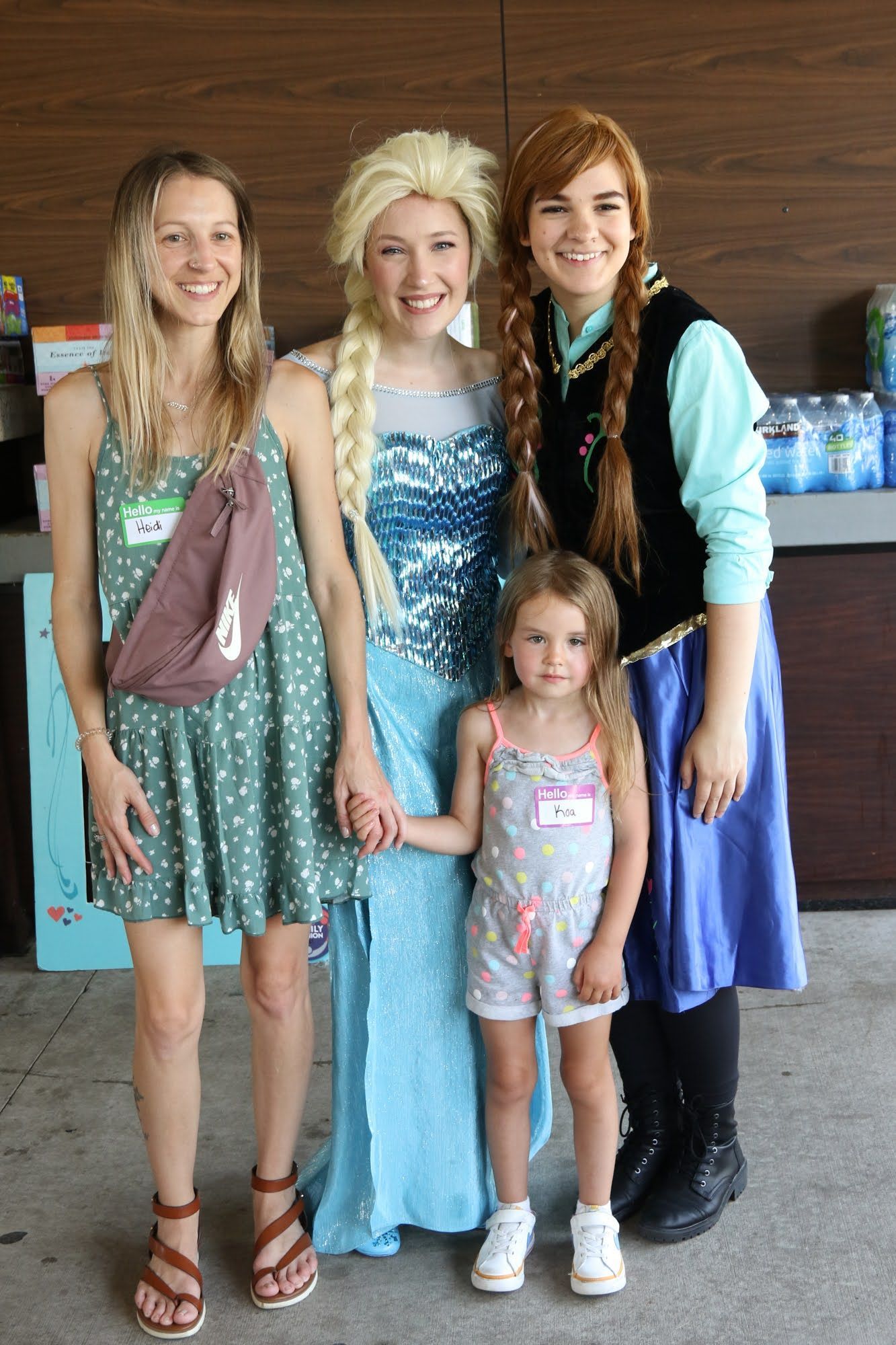 Two costumed Frozen characters pose with two women and a young girl at an outdoor event.