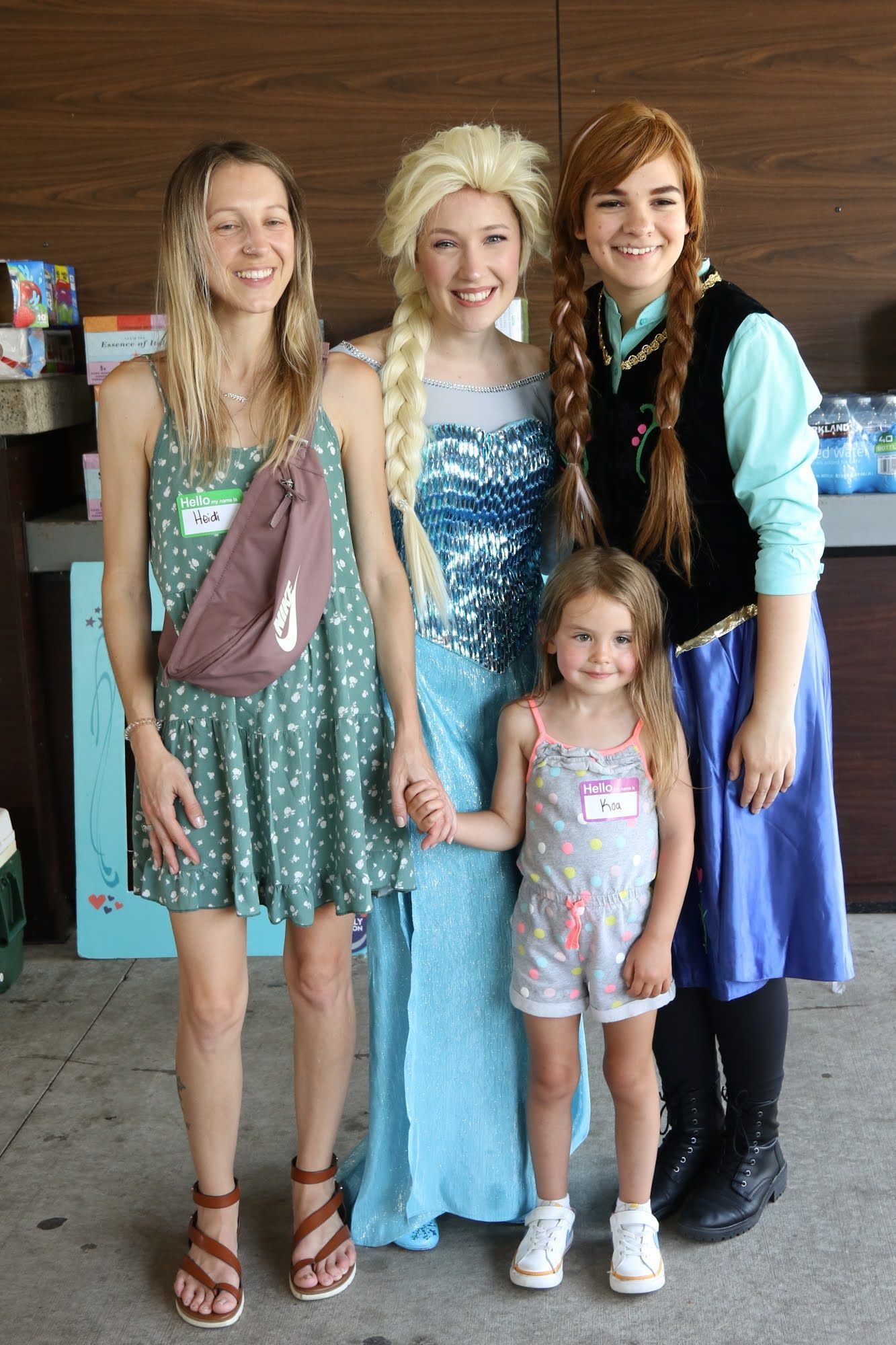 Group posing with Elsa and Anna characters at an outdoor event.