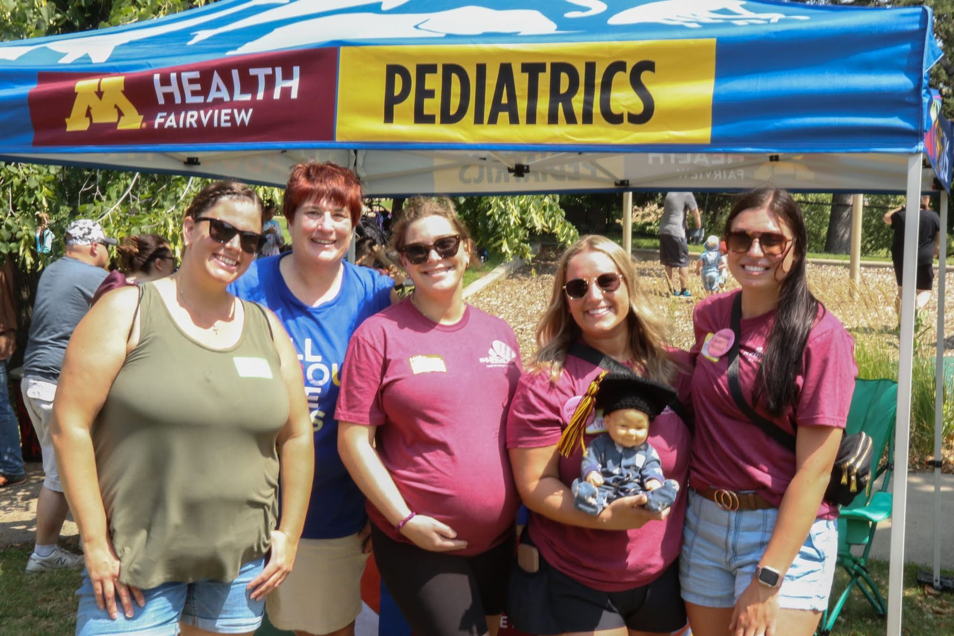 Health Fairview Pediatrics booth with five people posing outside; one holding a doll.