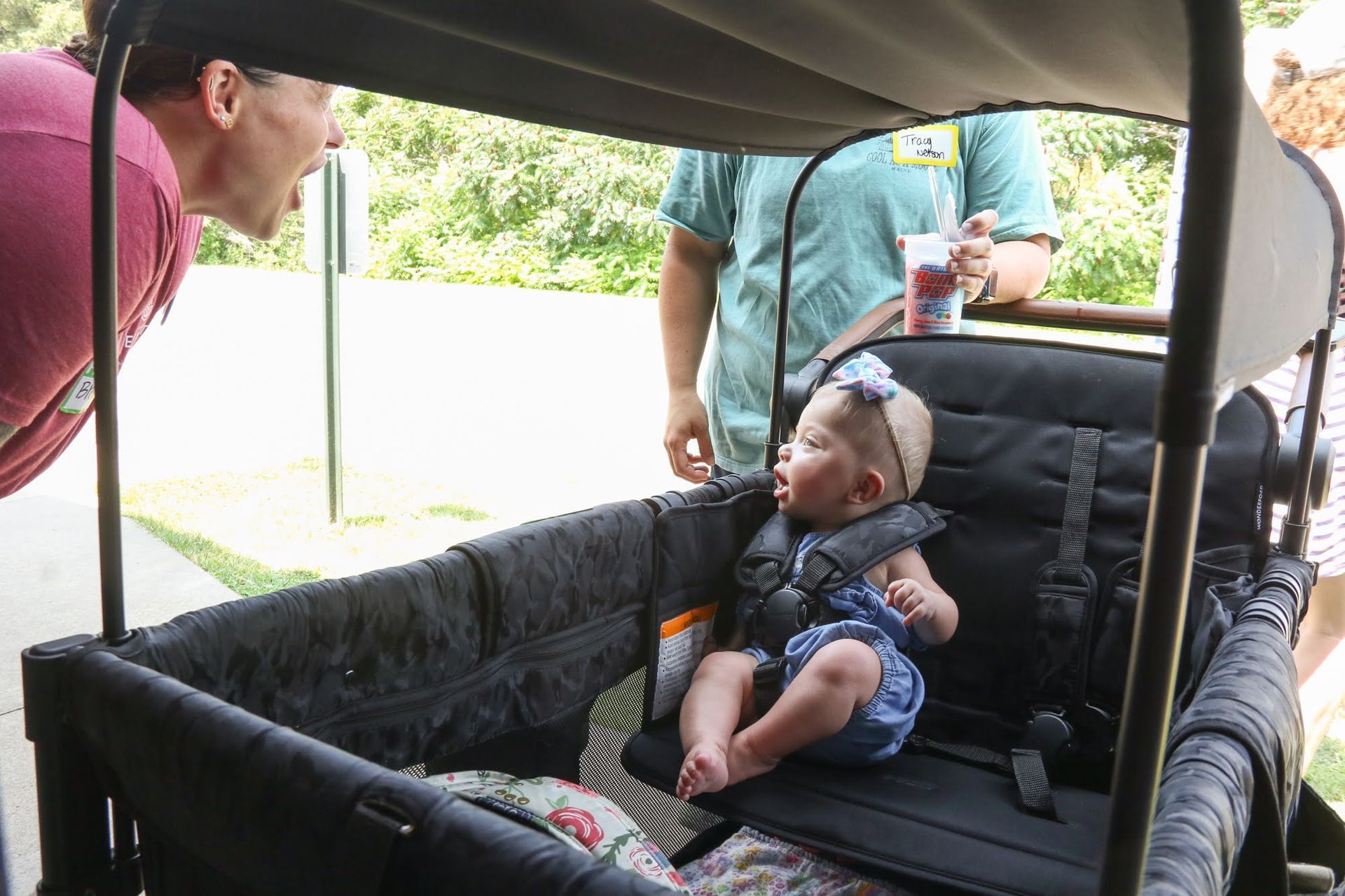 Baby in wagon, looking up, with a person yelling.