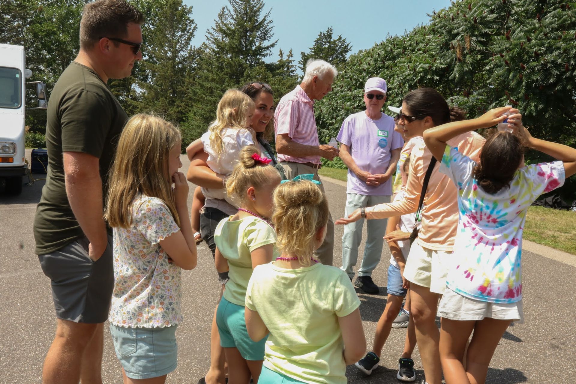 A group of people standing outside talking, some wearing tie-dye shirts.